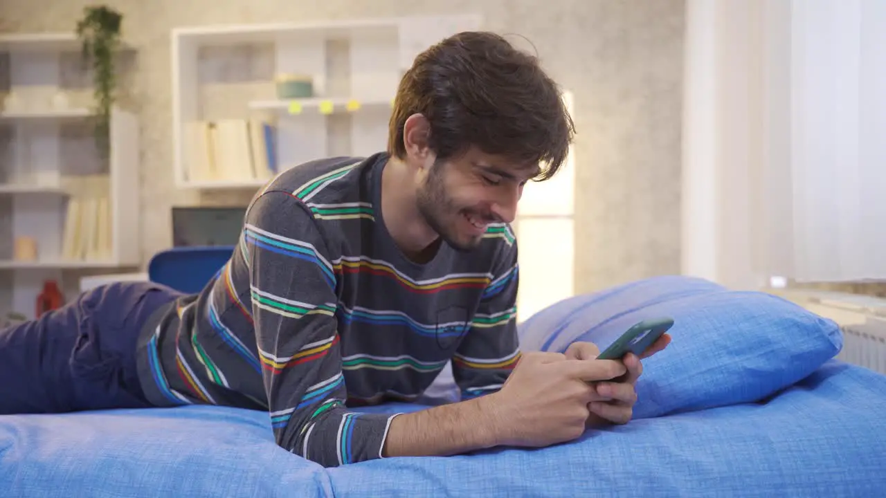 Young man texting on the phone in his room