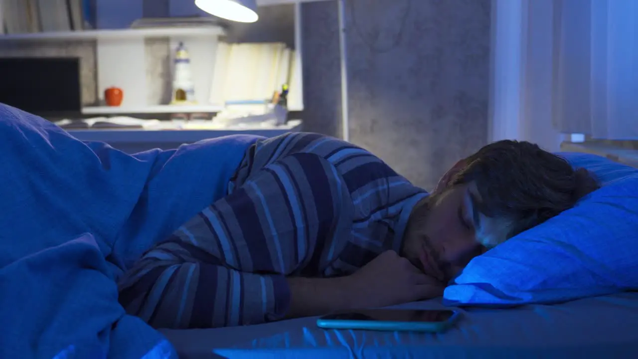 Phone addicted young man checking his phone even in his sleep