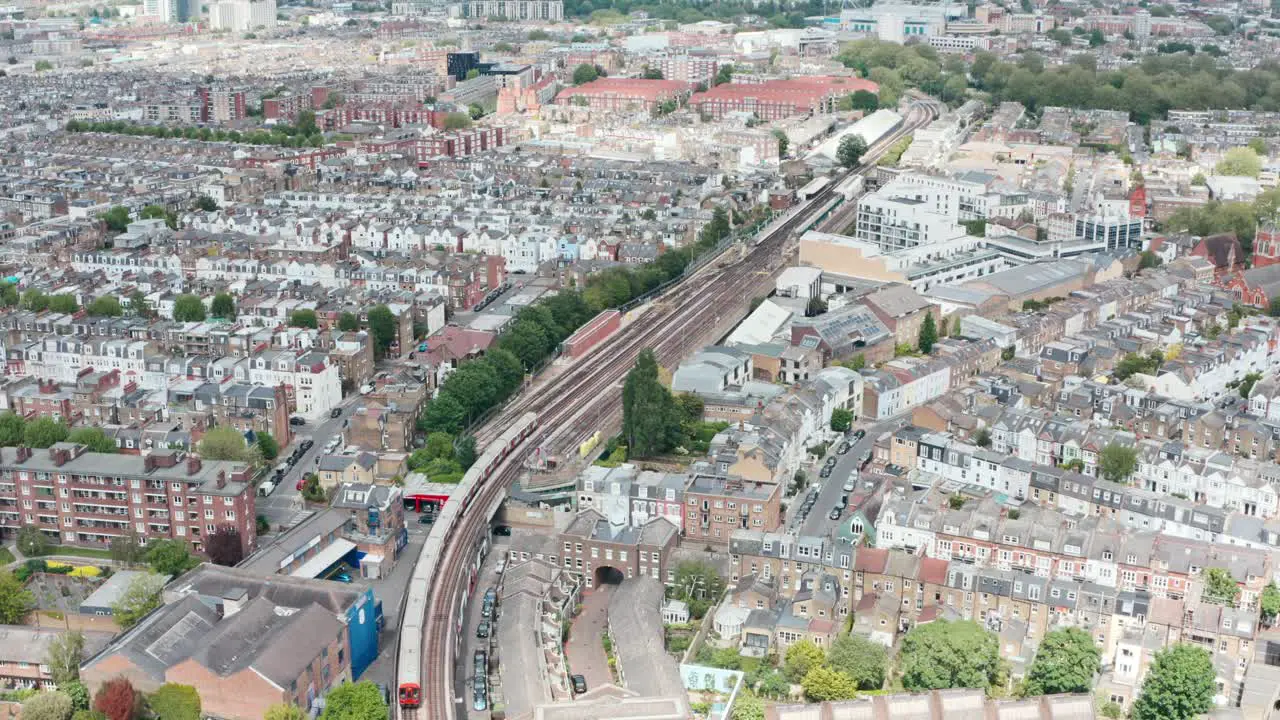 Follow drone shot of London underground train arriving at parsons green station