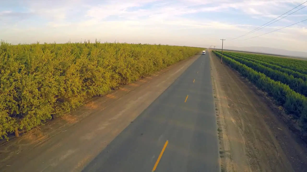 An aerial view over a truck passing over almond orchards