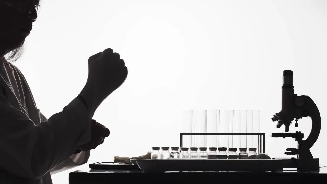 Silhouette of a scientist in a laboratory puts on latex gloves before experimenting time lapse with white background and copy space