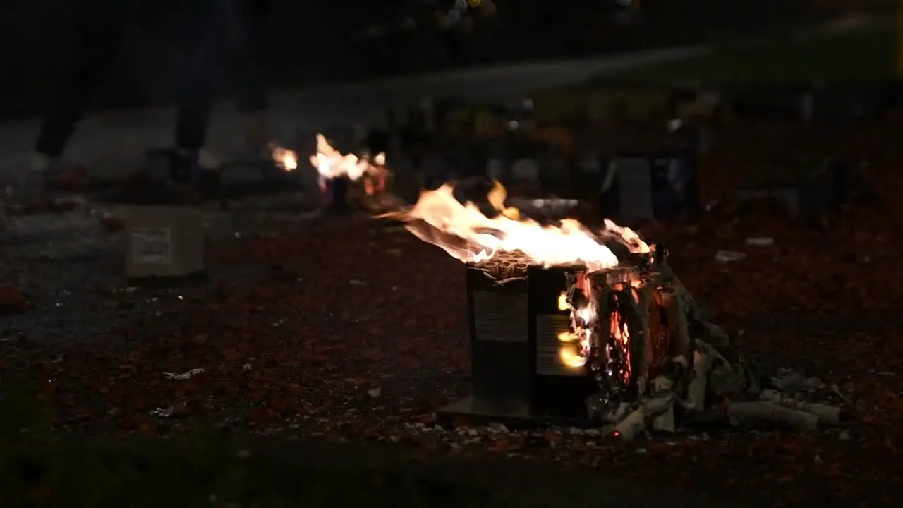 slow motion close up view of burning firework cake with fireworks being set off in the background