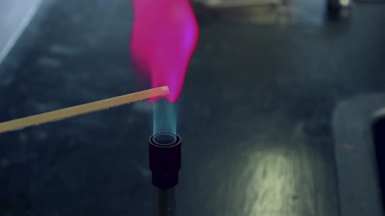 Close up of blue bunsen burner flame followed by lithium flame test burning magenta