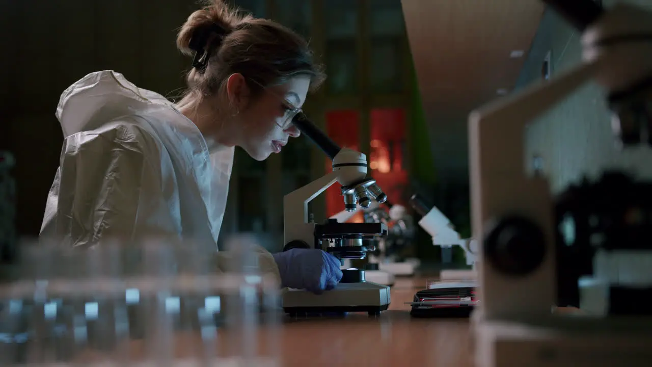 A young beautiful female scientist works with a professional microscope in the laboratory—medium shot