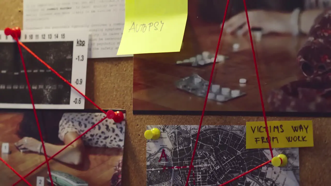 Detective's hands place yellow sticky note on evidence board