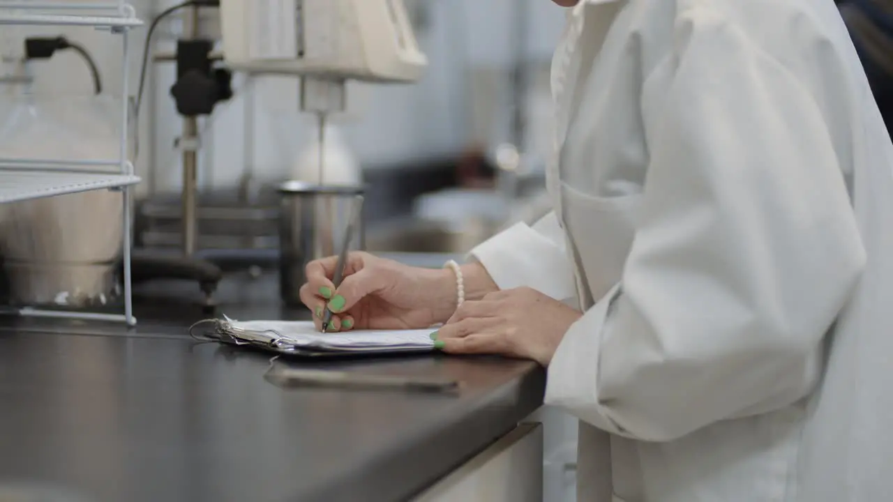 White coat female scientist in lab taking research notes on experimentation