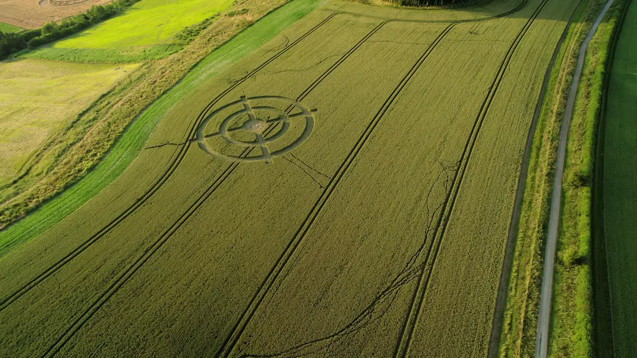 Hackpen hill strange crop circle target pattern in rural grass farmland meadow aerial view descending above countryside landscape