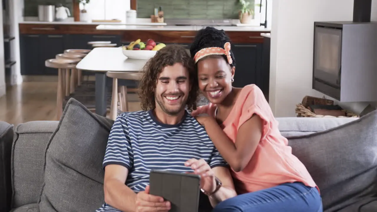 Diverse couple enjoys a tablet in a cozy home setting