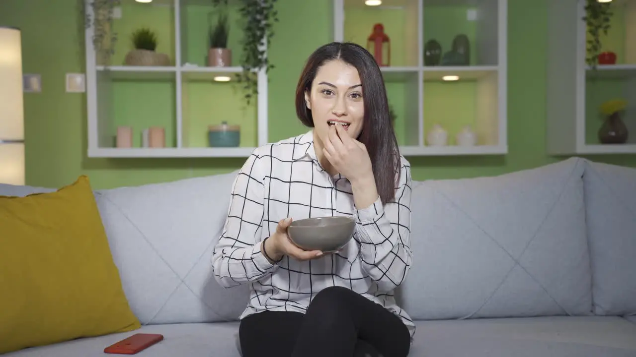 Young woman watching tv at home is happy and pleasant