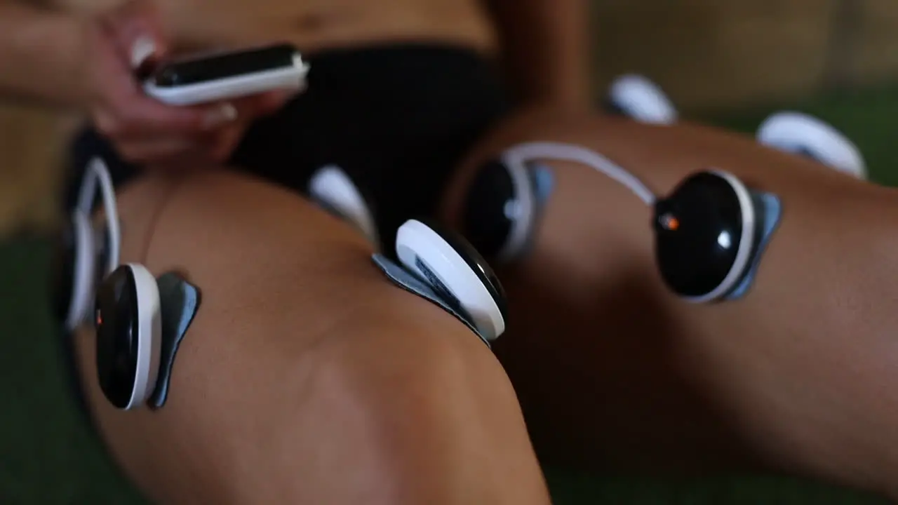 close up footage of electro vibration massage pads being used on an athletes legs