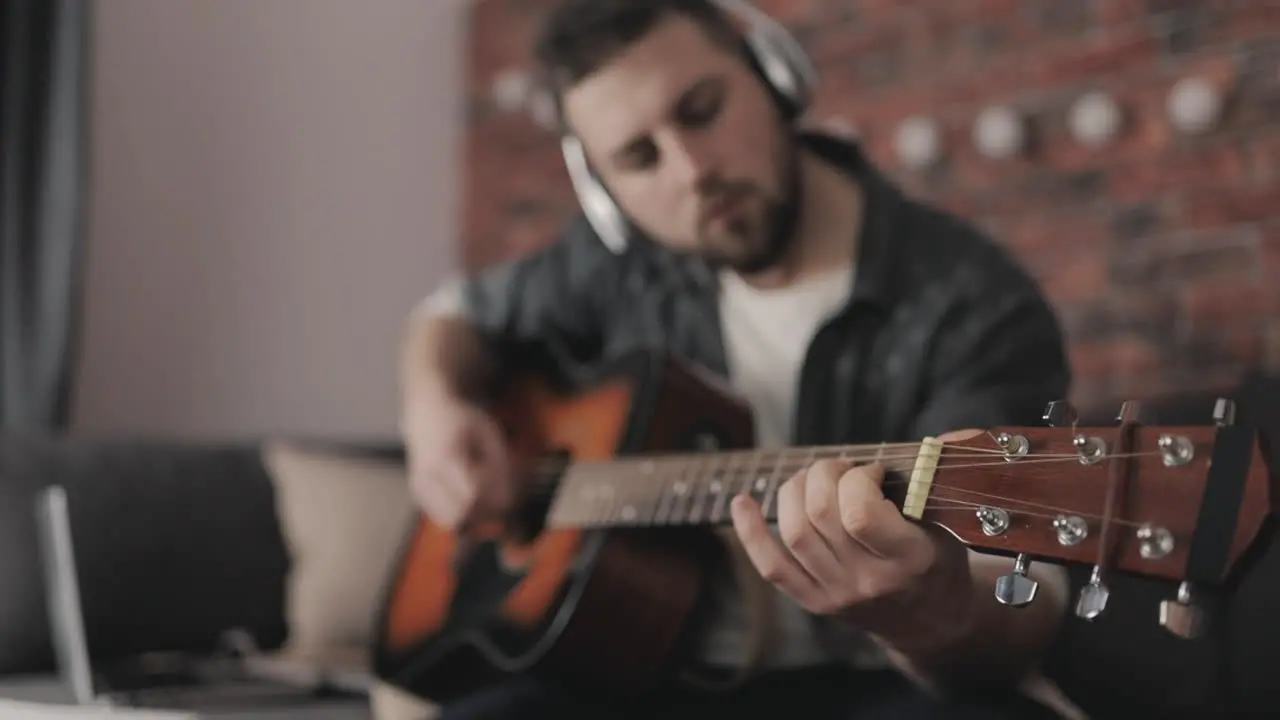 Young Man Musician Playing And Adjusting Guitar At Home