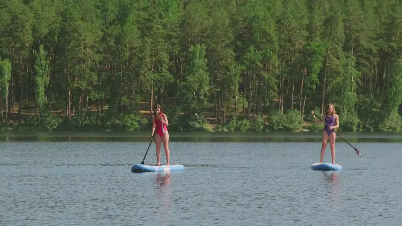 Aerial View Of Two Girls In Swimsuit Doing Paddle Surfing In The Sea