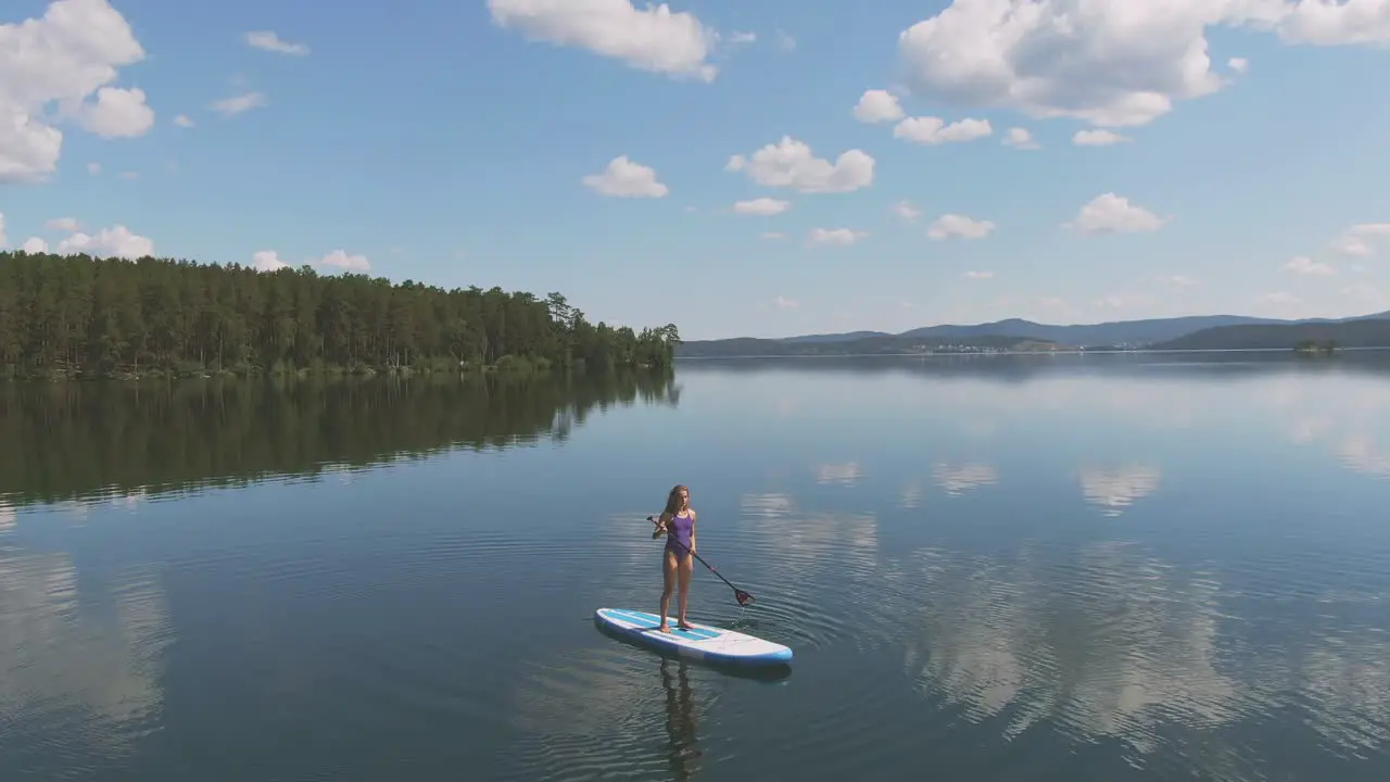 Aerial View Of Girl In Purple Swimsuit Doing Paddle Surfing In The Sea