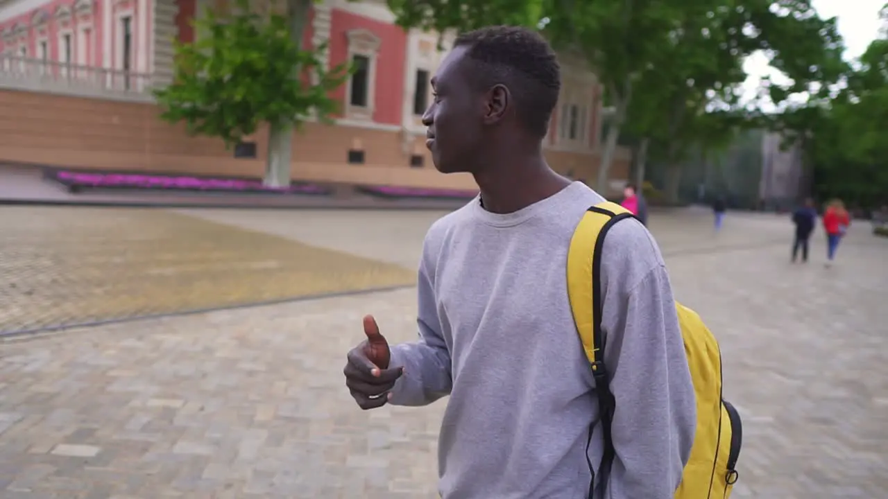 Funny Black Young Man Wearing Casual Clothes Yellow Backpack Enjoying Walking Dancing Of Fun On Sidewalk By City Street