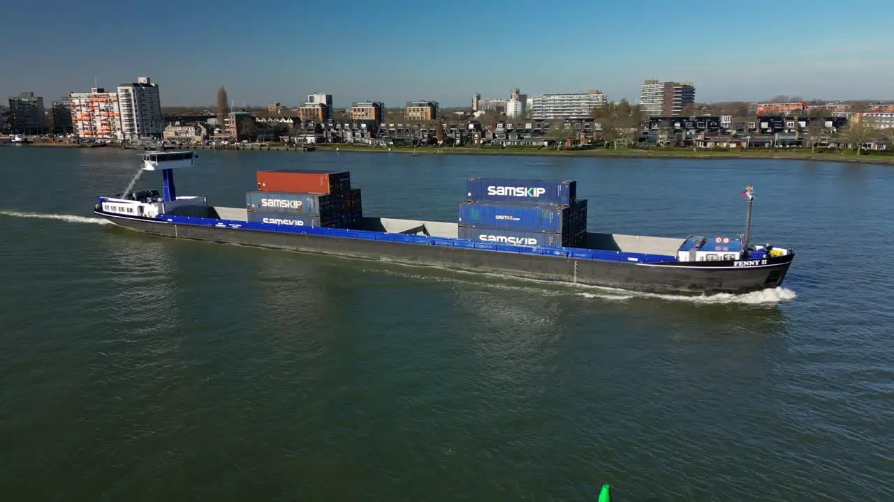 Aerial shot of a transportation ship with containers navigating towards the city Dordrecht The Netherlands