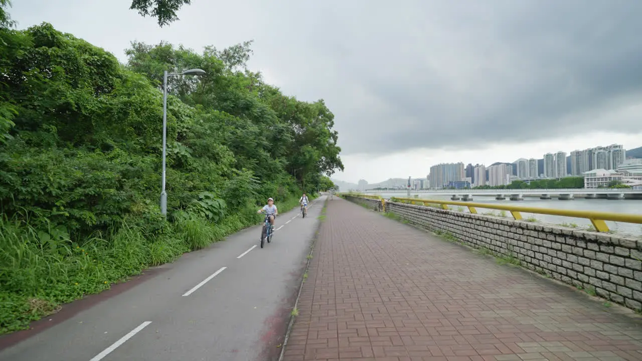 Urban Cycling Gimbal Shot of Bicycle Lane with River and Cityscape in Hong Kong