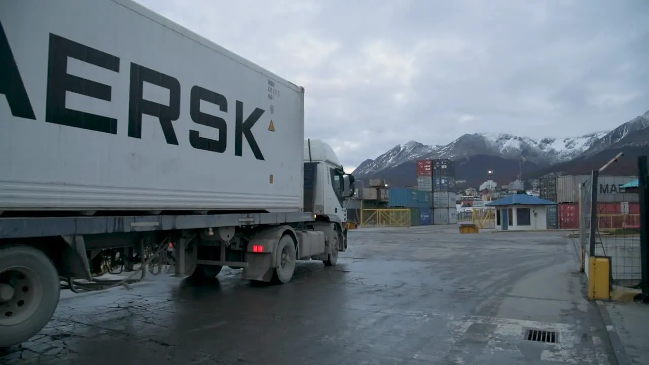 White semi truck at industrial Ushuaia port during dusk mountains in background overcast sky