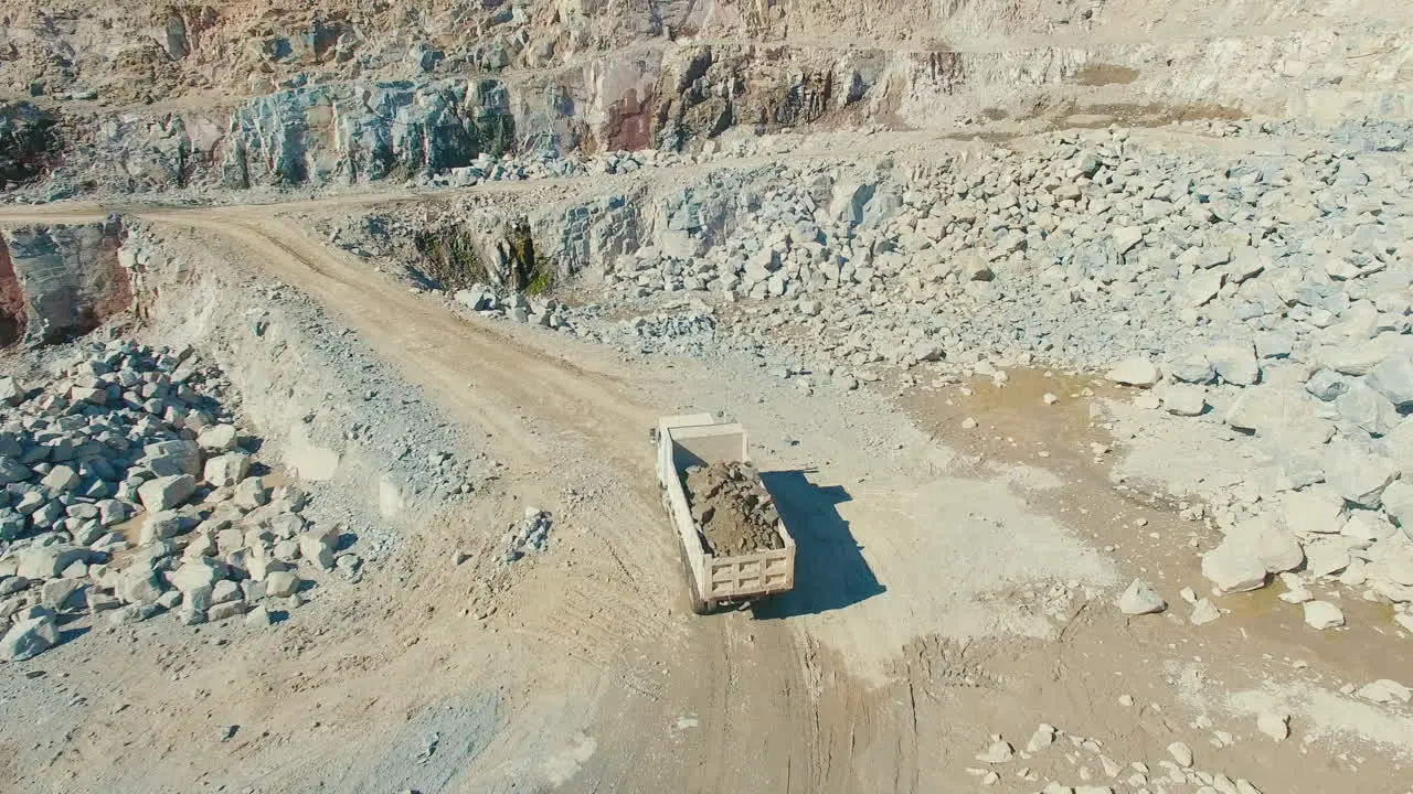 loaded truck driving in quarry mineral granite stone gravel pit wide aerial drone shot