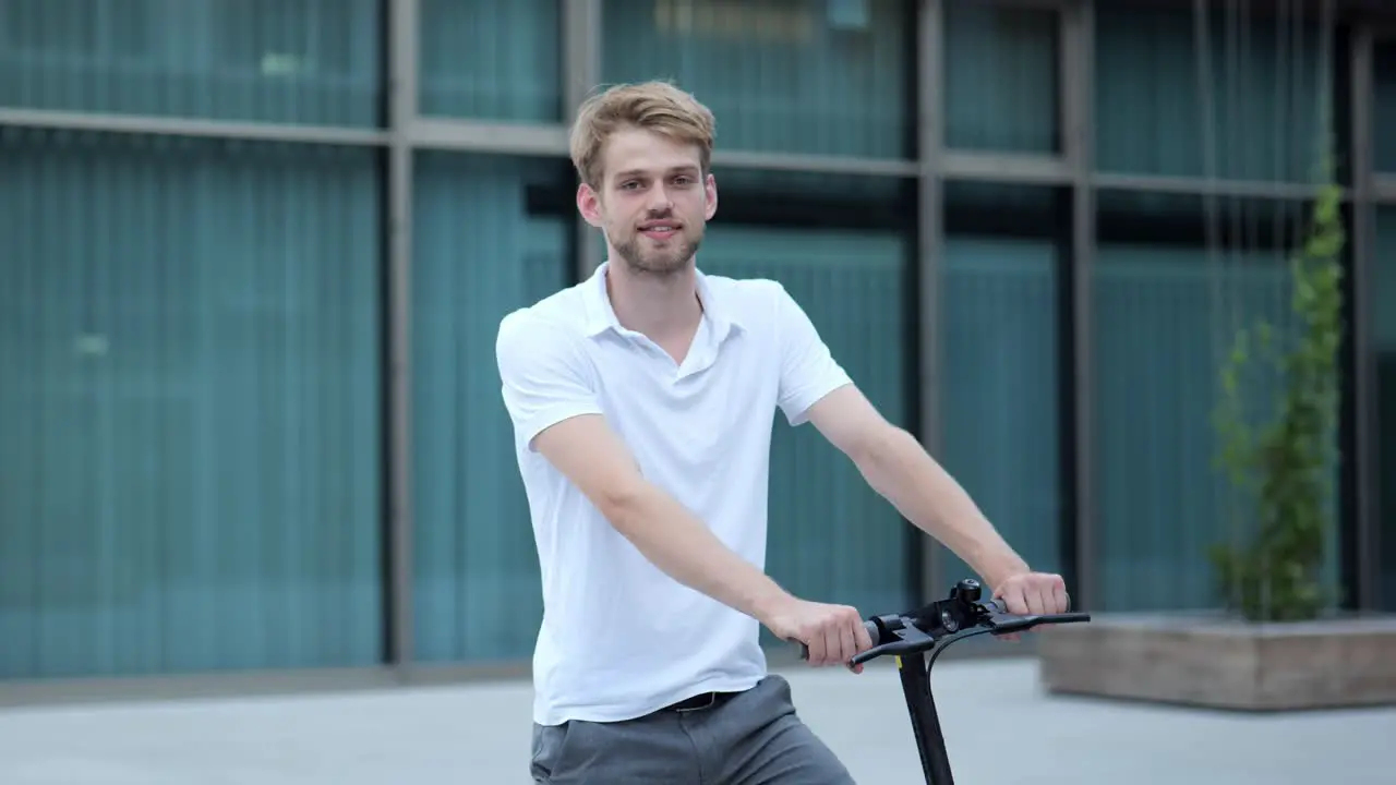 Young businessman standing on his e-scooter and smiling at the camera