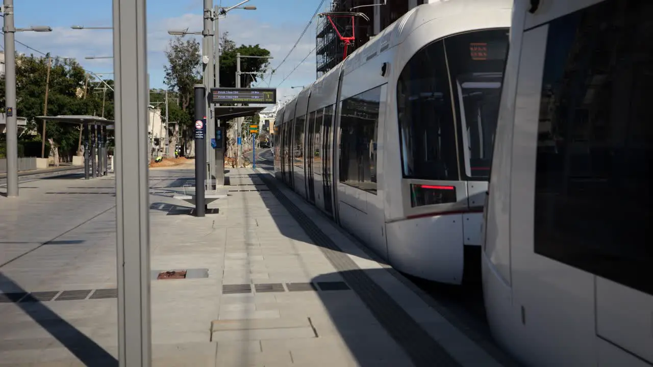 Tram arriving at the light rail platform with cyclist passing by establishing shot