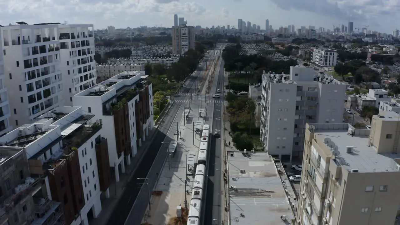 New light rail train driving through Tel Aviv city center aerial establishing shot