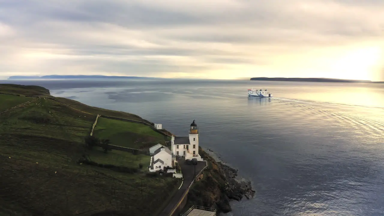 Spectacular drone shot with Ferry departing from harbour into beautiful sunset passing lighthouse