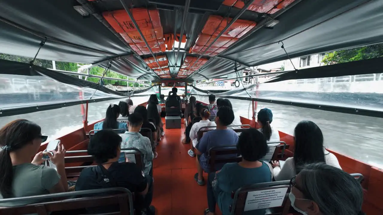 Interior view of a crowded water taxi with people on board and a woman busy texting on her mobile phone