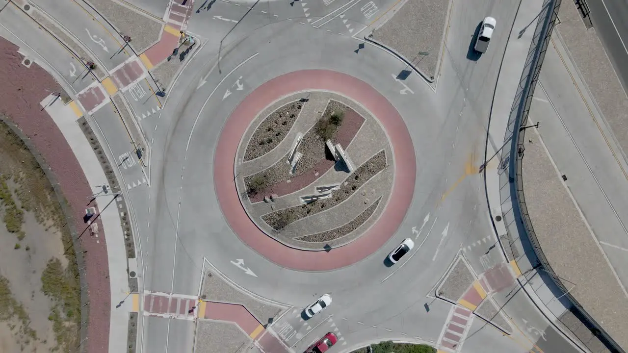 Drone's top-down view of a busy roundabout with personal and commercial vehicles in the early afternoon