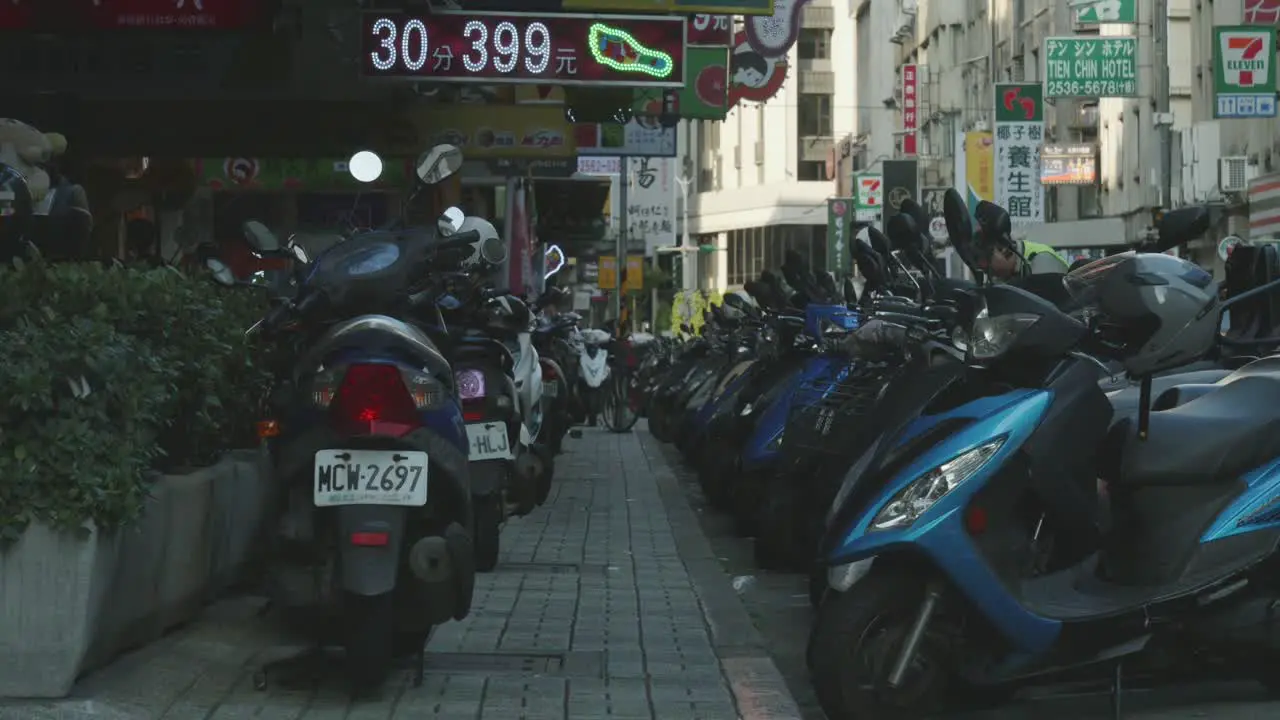 Row of parked scooters lining a busy street in Zhongshan Taipei during daytime city life