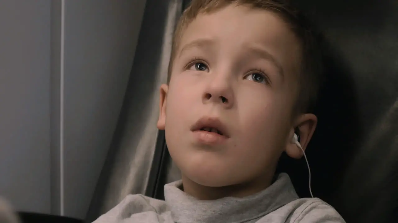 Boy watching TV in train he listening audio with earphones