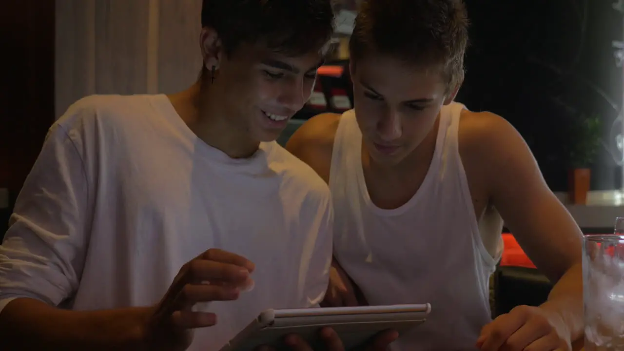 Two teen friends with tablet computer in cafe