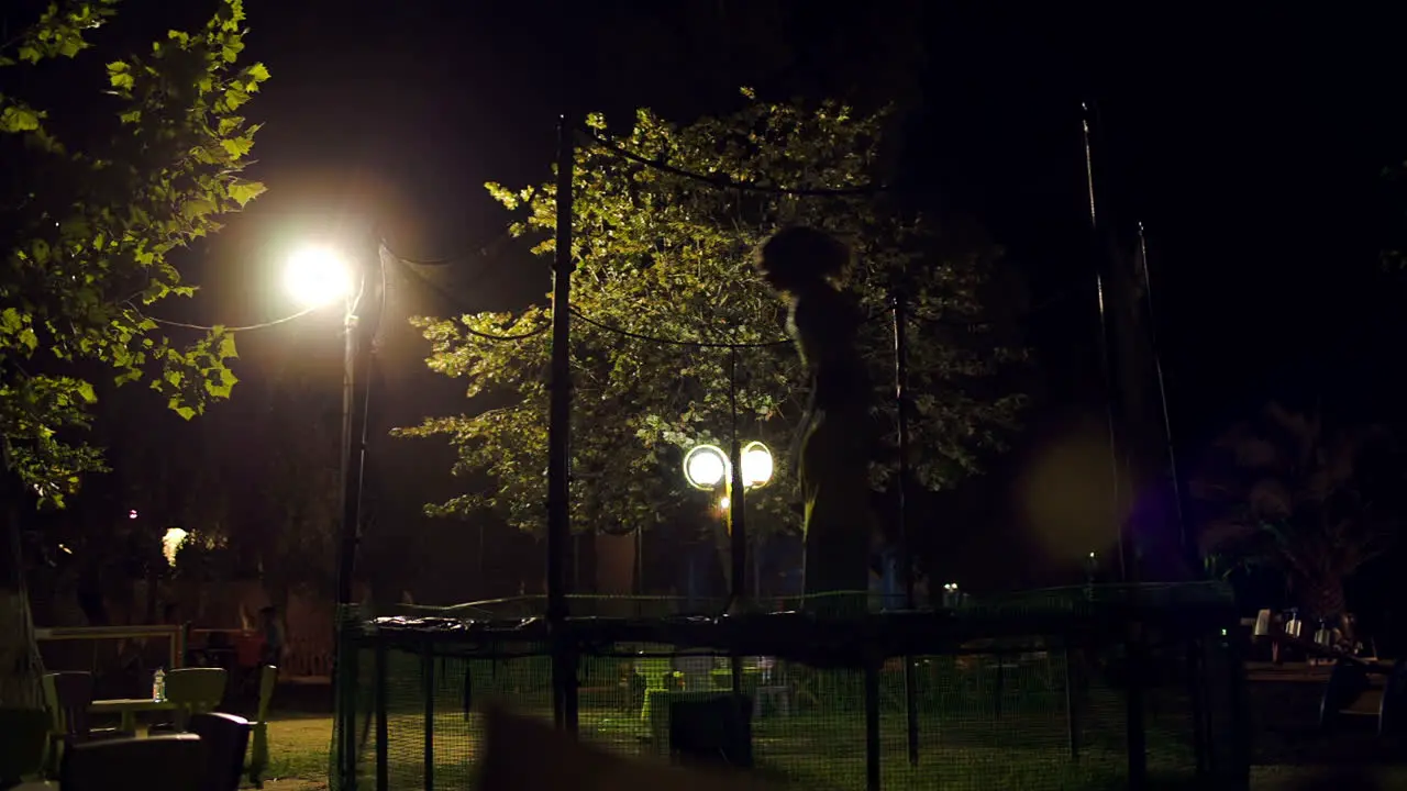 Children jumping on trampoline at night