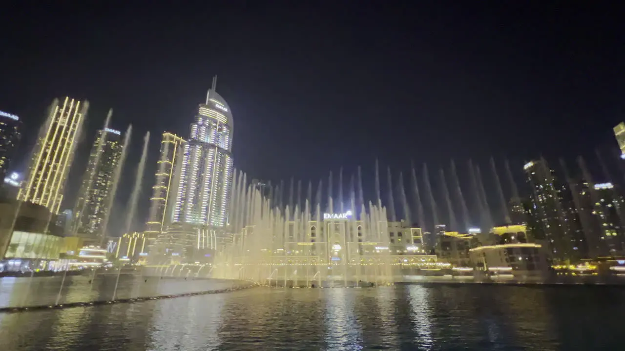 Wide view with the water show from Dubai fountain seen at night with the cityscape as a background