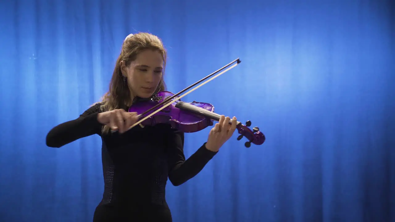 Young musician woman playing violin on stage