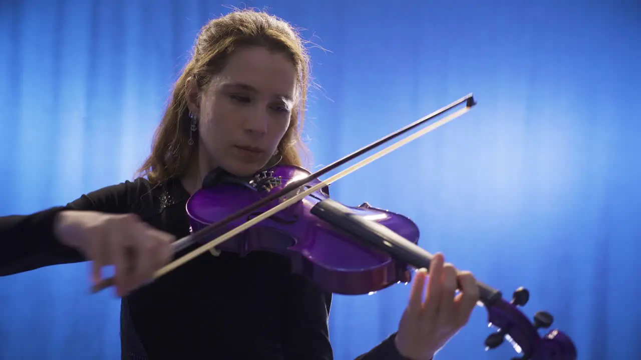 Close-up of young female musician playing violin on stage and her violin