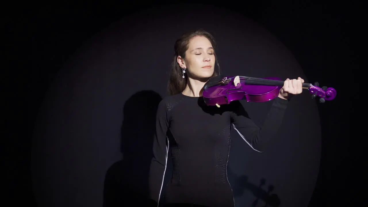 Young musician woman on stage playing the violin