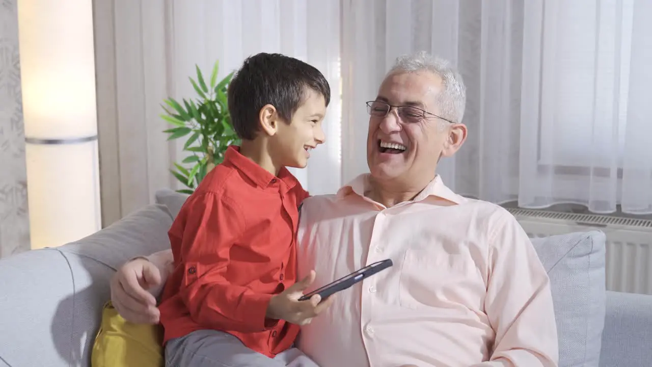 Father and son are laughing and looking at something fun on the phone