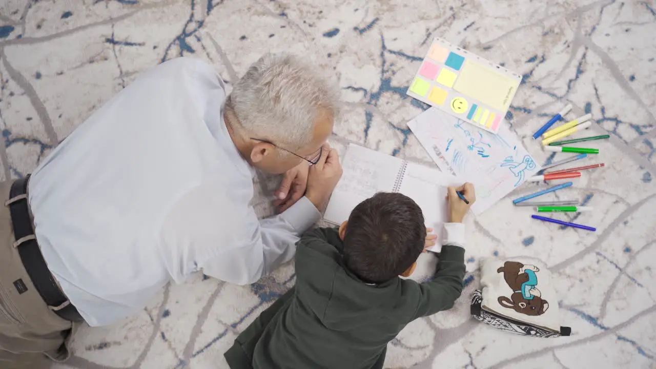 Father and son draw pictures and do homework at home