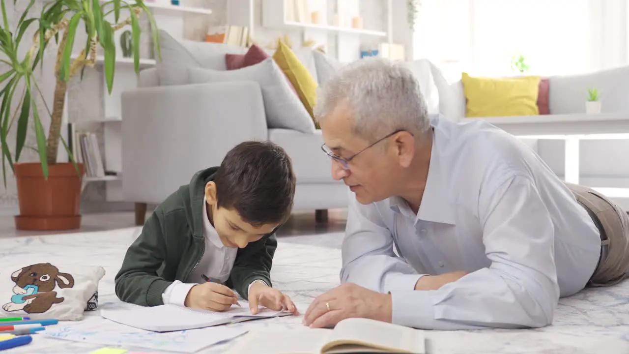 The father is tutoring his son and helping him with his lessons 