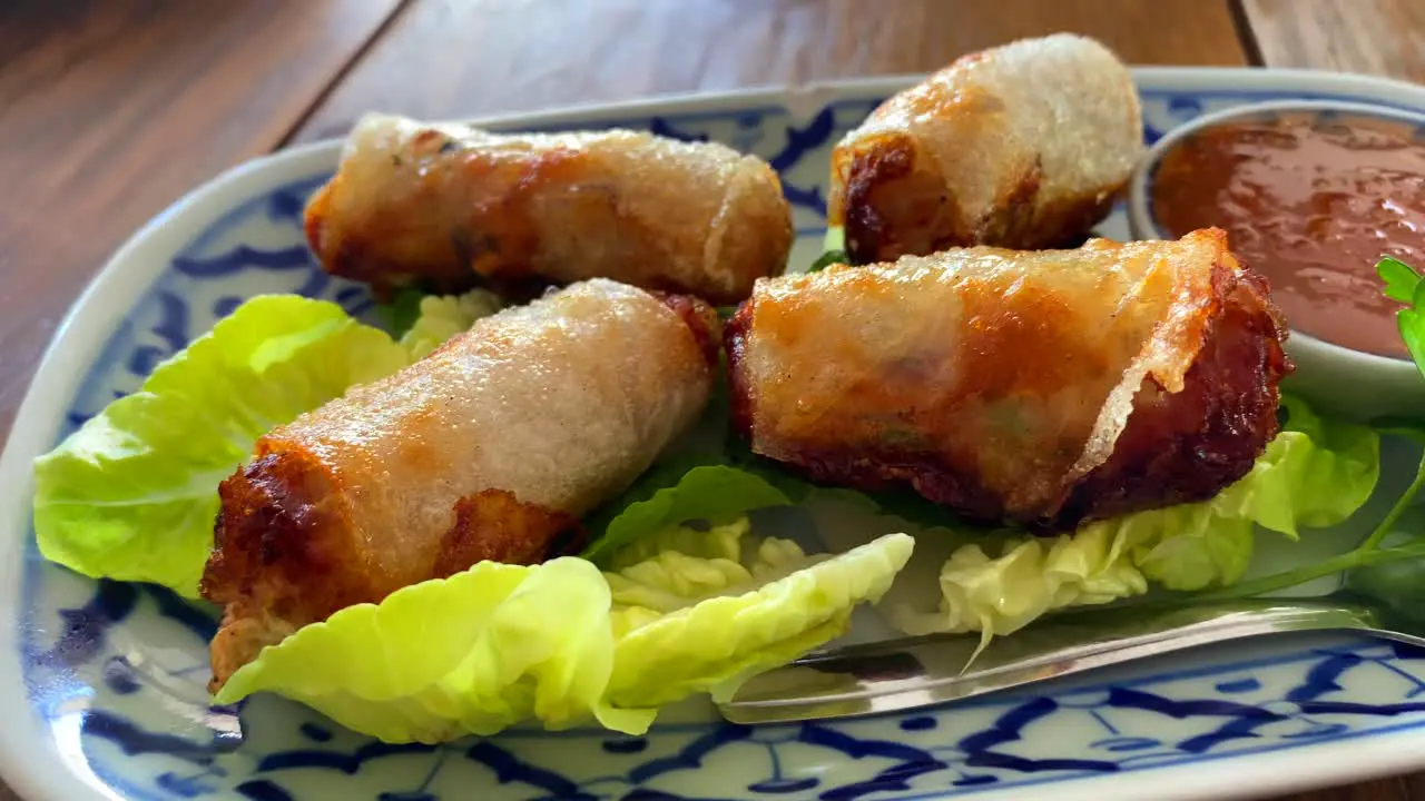 Traditional spring rolls on lettuce with sweet chili sauce in Thai restaurant asian food starter for lunch 4K shot