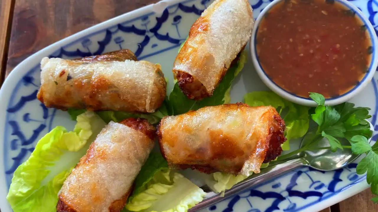 Traditional spring rolls on lettuce with sweet chili sauce in Thai restaurant asian food starter for lunch 4K top view shot