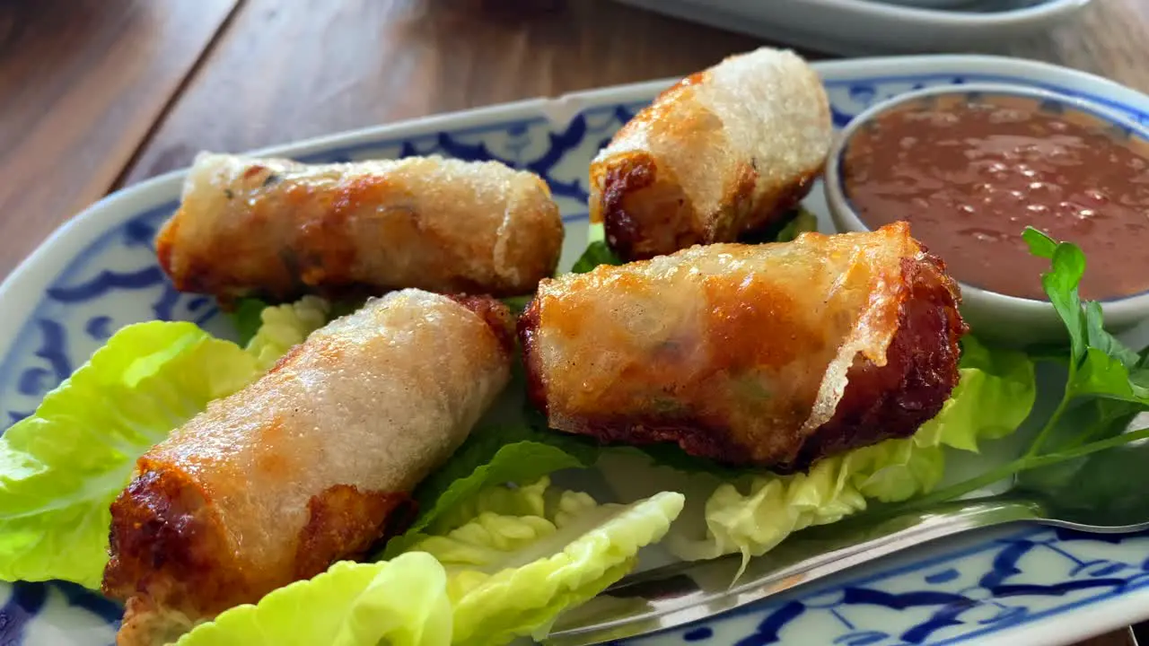 Traditional spring rolls on lettuce with sweet chili sauce in a Thai restaurant asian food 4K shot