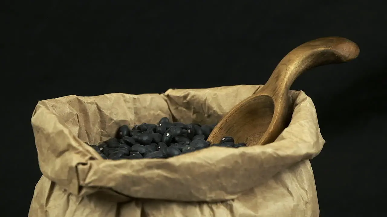 Narrow depth of field Dry black beans rotate in paper bag dark room