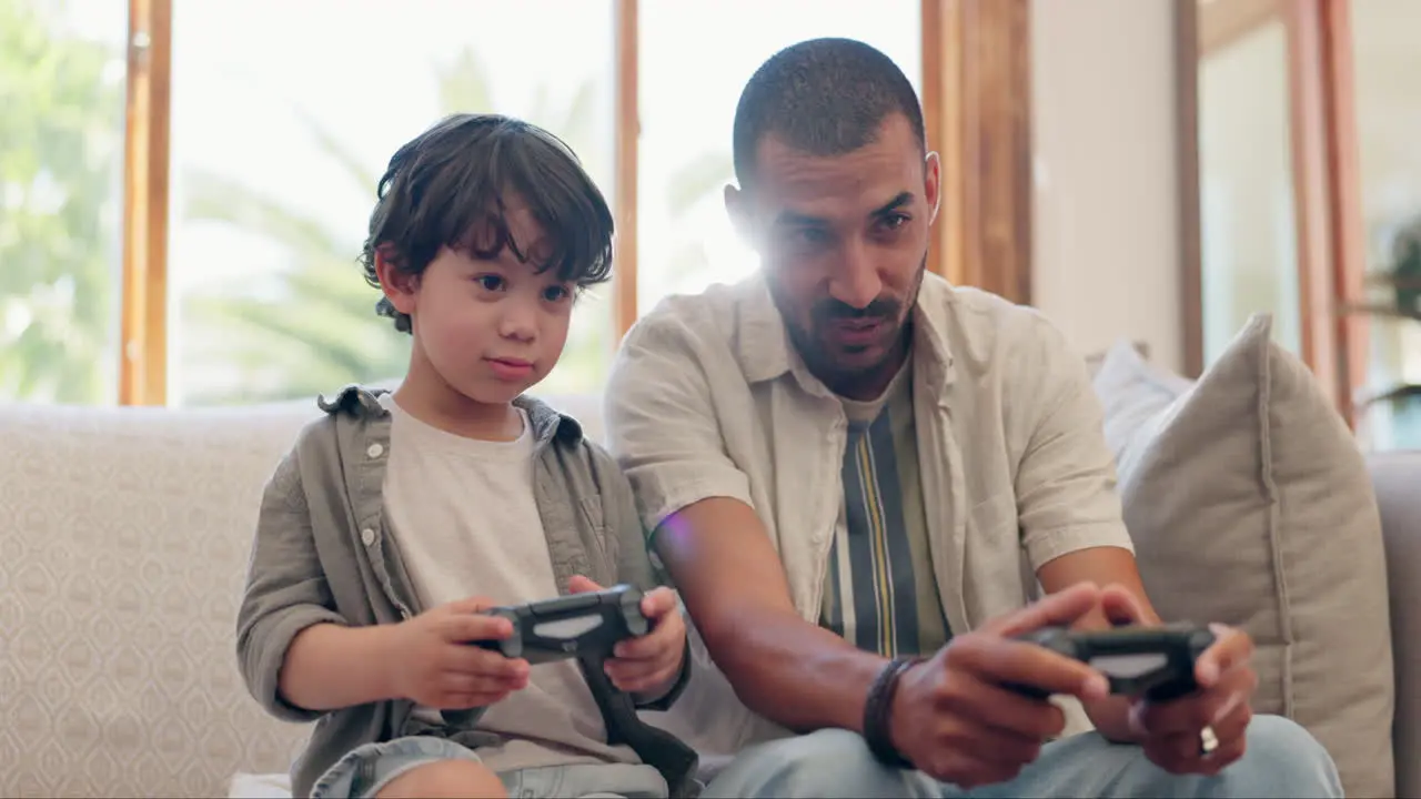 Father boy and video game controller on sofa