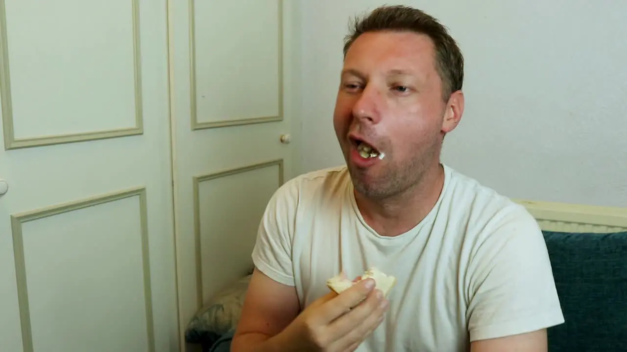 A man eating a sandwich watching tv