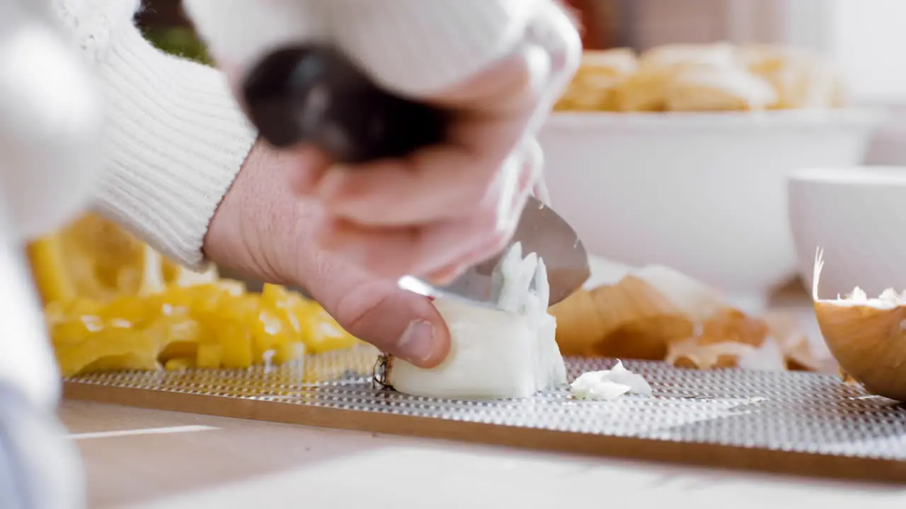 Male professional chef cooking food dinner hacking yellow onion with sharp knife on cutting board making delicious tasty fancy dinner romantic date cooking stew pasta spicy food sunny kitchen home dad