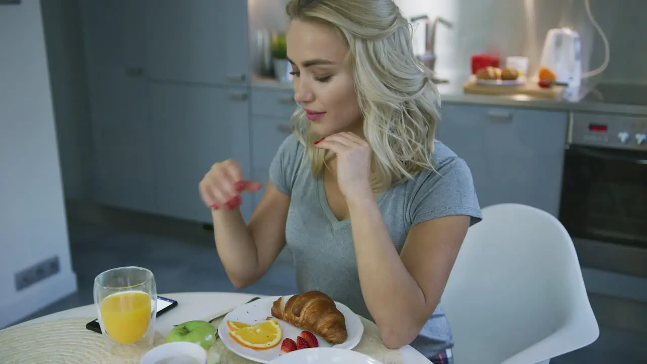 Smiling woman browsing smartphone during breakfast