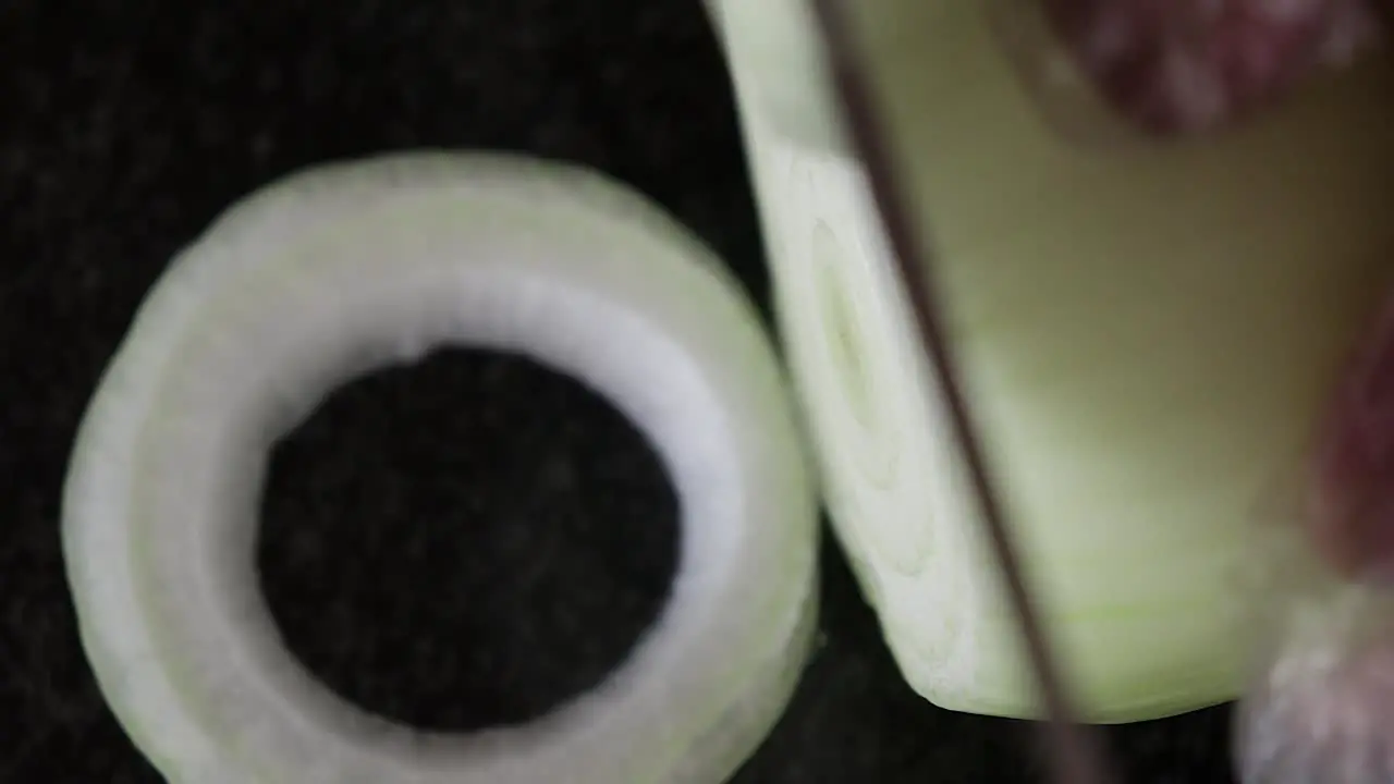 A close up top shot of an onion being cut into rings