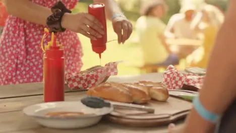 Close Up Shot of Festival Goer Adding Sauce to Hot Dog