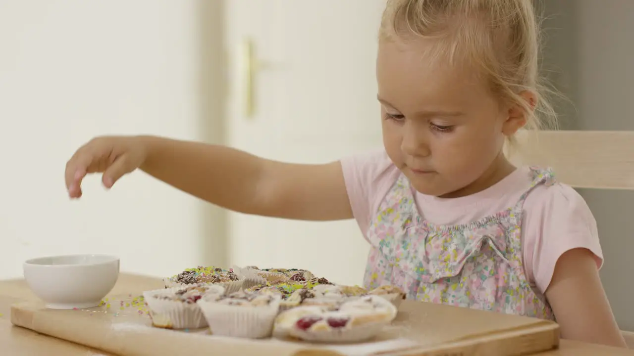 Close up on girl sprinkling toppings on muffins